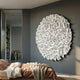 Eclat Sphere White Abstract Metal Wall Art by Giant Sculptures mounted on a grey bedroom wall above a bed with rust bedding, near a bookshelf-lined hallway.