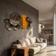 Luminis Bloom Yellow Floral Metal Wall Art by Giant Sculptures mounted on a grey wall above a beige sofa in a modern living room near an open kitchen.