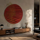 Auramesh Crimson-I Metal Winged Circular Geometric Wall Art mounted above a walnut sideboard in a warm living room with lamp, vase, and books.