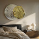 Metaluxe III Gold & Silver Dual Disc Textured 3D Wall Art by Giant Sculptures mounted above a black leather bed with linen bedding and a walnut nightstand.