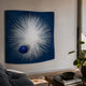 Astralis Stellar Burst Abstract 3D Wall Art by Giant Sculptures mounted above a sofa, with white radiating spikes and a glossy blue sphere on deep blue.