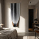 Celestial Flow Waterfall metal wall art by Giant Sculptures, mirror-polished steel cascade with warm bronze base, mounted above a bed in a neutral bedroom.