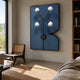 Axial Elegance Blue Symmetrical Metal Wall Art by Giant Sculptures displayed in a sunlit bedroom above a cane lounge chair beside a wooden bookshelf.