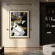 Eterna Classics Athena Replica Portrait Golden Frame Wall Art suspended from a gold bar bracket on a concrete wall beside a dark bookshelf in a modern lounge.
