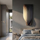Celestial Luminous Skyline Curved Vertical Abstract Metal Wall Art in glossy black and gold mounted above a bed in a modern grey bedroom with brass floor lamp.