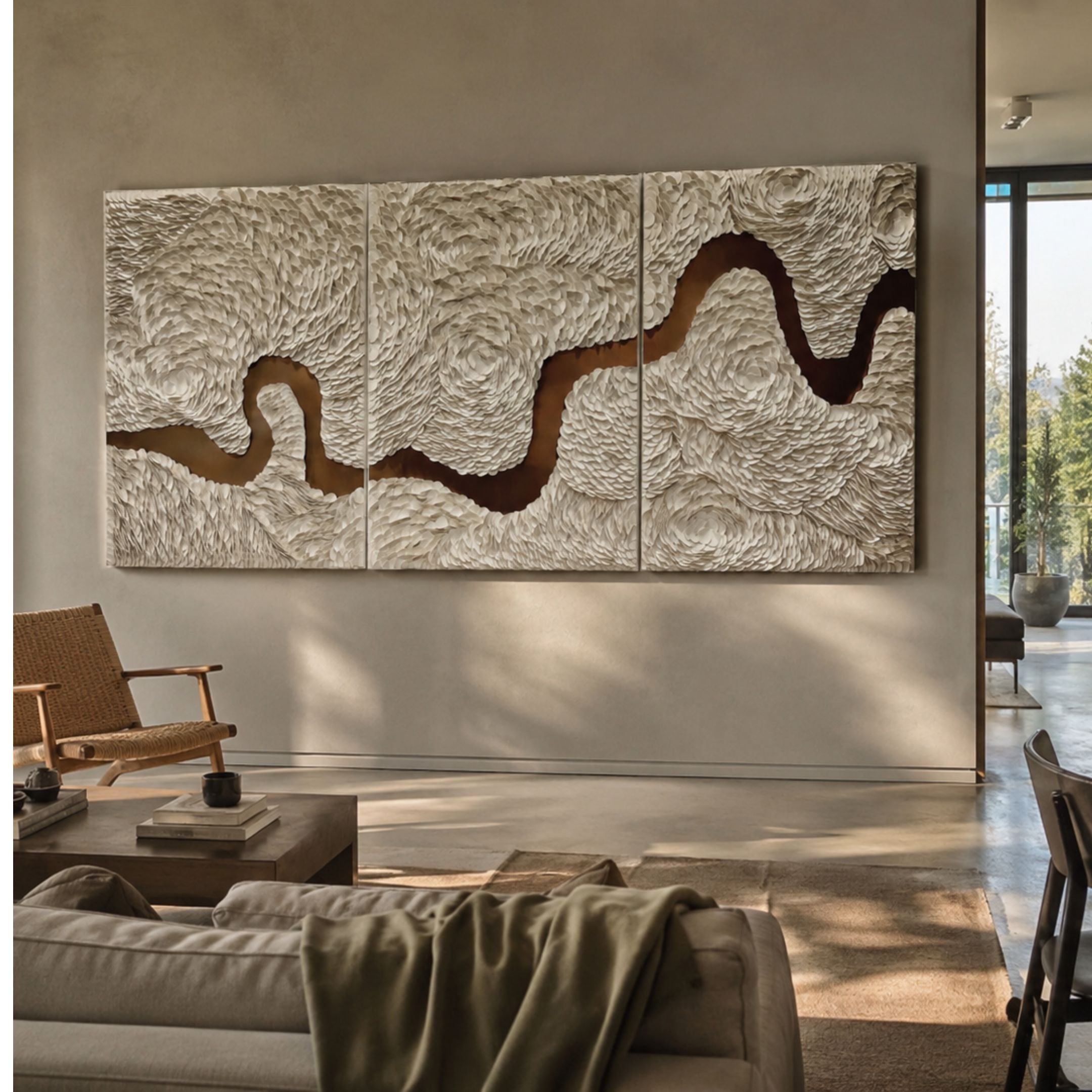 Riverine Flow Pearl White Textured Triptych Wall Art by Giant Sculptures mounted above a sofa in a neutral living room with a woven chair nearby.