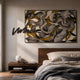 Graffio Abstract Yellow Swirl Wall Art by Giant Sculptures, with grey and black brushstrokes over yellow, displayed above a wooden nightstand in a modern bedroom.