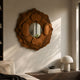 Sculptura Mirror Warm Brown Floral Round Metal Wall Art mounted above a dark wood console with a dome lamp, in a sunlit neutral living space.