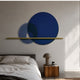 Luna Forma Midnight Blue Round Brass Accent Wall Art mounted above a grey upholstered bed with a wooden cube nightstand and mushroom lamp.