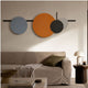 Orbit III Dynamic Flow Multicoloured Circular Wall Art by Giant Sculptures, with blue, orange, black, and grey discs on black linework above a beige sofa.