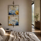 Vortice Bloom Symphony Floral Dual Panel Wall Art by Giant Sculptures, two stacked square panels with blue, yellow, and white abstract blooms, displayed above a linen-dressed bed.
