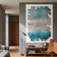Lumora Aqua Mosaic 3D Wall Art by Giant Sculptures, a tessellated blue and white tile composition framed in white, mounted above a wooden console in a modern living room.