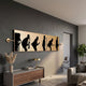Resonance Musical Evolution Silhouette Wall Art by Giant Sculptures, a long horizontal gold and black plaque of figures progressing into a guitarist, above a walnut console in a grey living room.