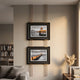 Imperia Serene Lakeside View Dual Frame Metal Wall Art by Giant Sculptures, two black-and-gold framed lakeside photographs suspended by brass rods above a sofa.