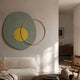 Solaro Calming Green & Yellow Round Mural Wall Art by Giant Sculptures, a textured green-grey oval with yellow centre and gold ring, above a cream sofa.