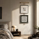 Artisera Grid Motif Dual Frame Built-In Light Wall Art mounted above a wood nightstand in a neutral bedroom, with grid and angular black motifs in black, white, and green.