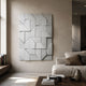 Prisma White Geometric Panel 3D Wall Art by Giant Sculptures mounted on a beige wall in a modern living room with a neutral sofa and wooden coffee table.