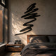 Oscura Energy Spiral Black Abstract Wall Art by Giant Sculptures, a matte black zigzag iron line mounted above a wooden nightstand in a sunlit bedroom.