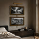 Artisera Ballet Noir Luxe Dual Frame Built-In Light Wall Art mounted above a dark wood console in a bedroom, with a ballet dancer image above a monochrome tram scene.