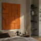 Prisma Orange Geometric Panel 3D Wall Art by Giant Sculptures mounted above a bed, beside dark wood shelves with books and a vase of branches.