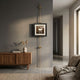 Ecliptica Abstract Architectural Column Gold Frame Wall Art suspended on a brass rod against a grey wall above a walnut sideboard in a modern living room.