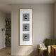 Lustre Black & White Plaster Statue Vertical Wall Art by Giant Sculptures displayed on a beige wall above a green velvet armchair beside a bookshelf.