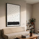 Ethore Textured Minimalist Silk Art Panel in a framed black and white composition above a beige sofa, beside a bookshelf with plants in a modern living room.