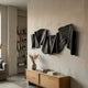 Rollscape Charcoal Flow Enamel Decorative Wall Art by Giant Sculptures, mounted above an oak console in a neutral living room with bookshelf and floor lamp.