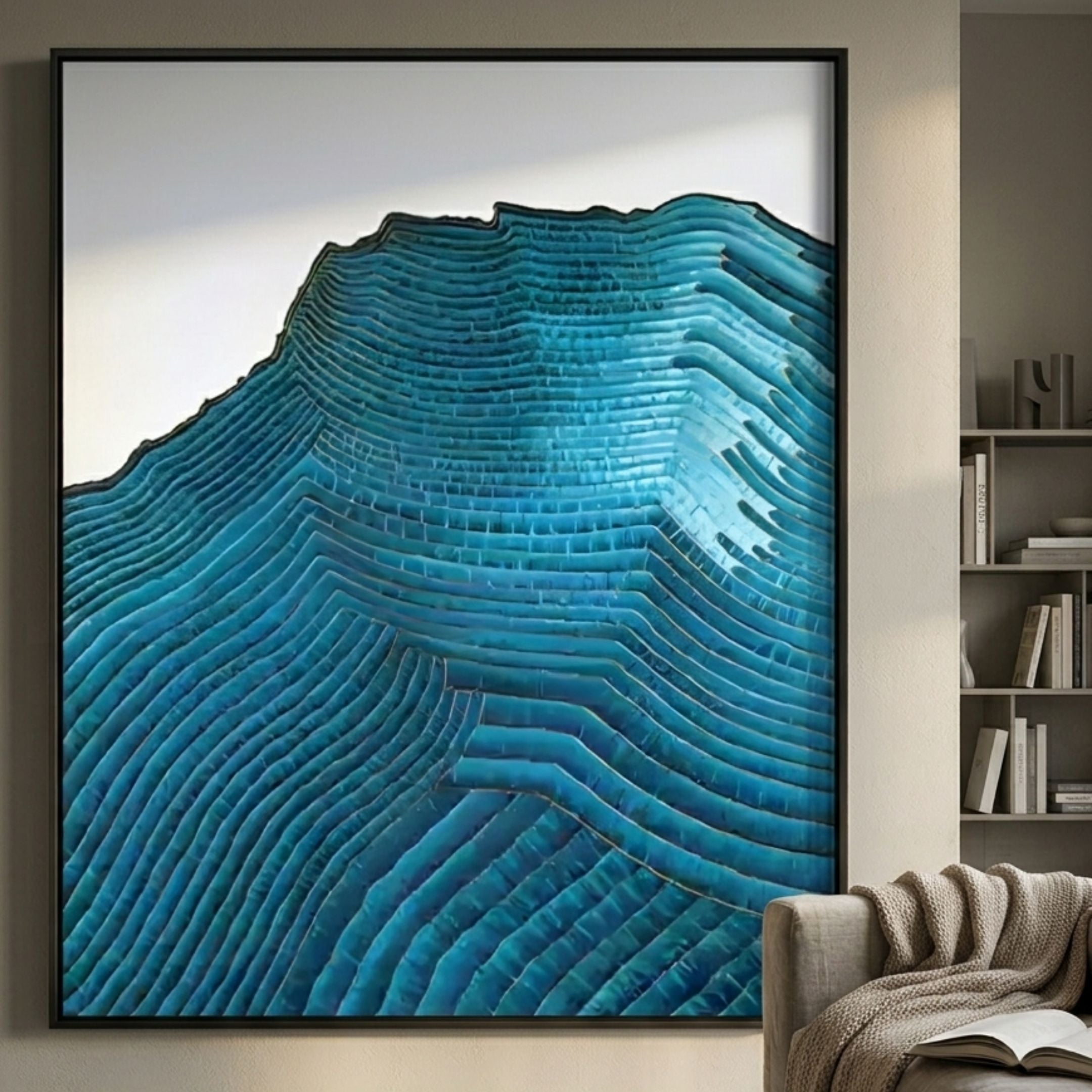 Ripplewave IV Abstract Blue Decorative Enamel Wall Art by Giant Sculptures, framed turquoise topographic contours displayed above a beige armchair beside a bookshelf.