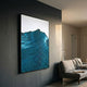 Ripplewave III Abstract Blue Decorative Enamel Wall Art by Giant Sculptures displayed on a dark grey living room wall above a beige sofa with throw blanket.