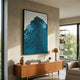 Ripplewave I Abstract Blue Decorative Enamel Wall Art by Giant Sculptures displayed above a mid-century wood sideboard in a sunlit living room with a brass lamp.