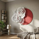 Fleur Halo Red Round White Metal Floral Decorative Wall Art mounted in a living room above a stone lamp, beside a bookshelf and linen sofa.
