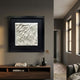 Harmonia 3D Wave Ceramic Wall Sculpture by Giant Sculptures, white sculpted relief in black frame, displayed above a walnut console in a grey hallway.