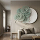 Fleur Halo White Round Green Metal Floral Decorative Wall Art mounted above a beige linen sofa in a neutral living room with floor lamp and timber flooring.