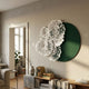 Fleur Halo Green Round White Metal Floral Decorative Wall Art mounted above a low bookshelf and vase in a sunlit neutral living room.