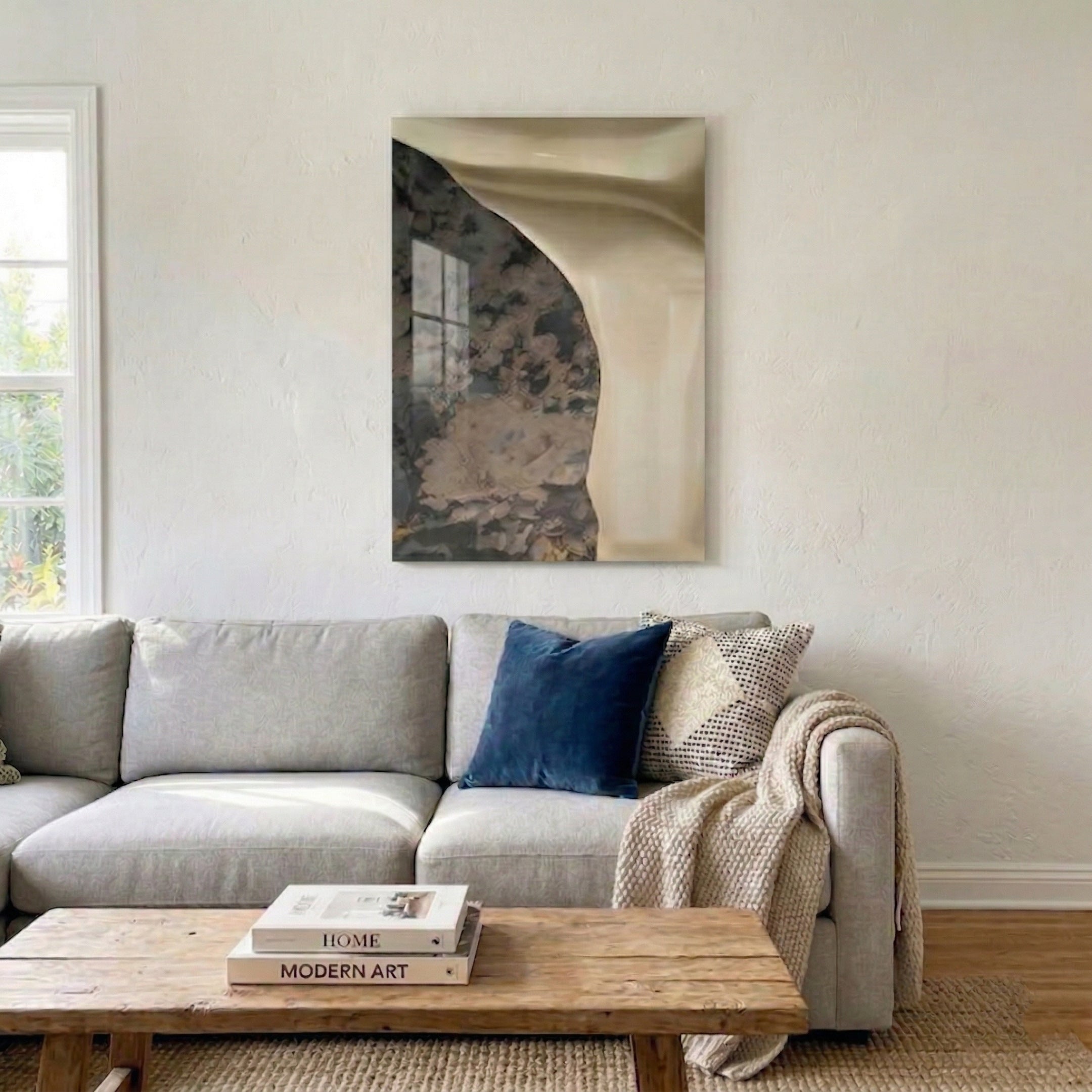 Gildrift Gold Steel & Ivory-Granite Curve Textured 3D Wall Art by Giant Sculptures displayed in a neutral living room above a light grey sofa with blue and patterned pillows and a wooden coffee table.