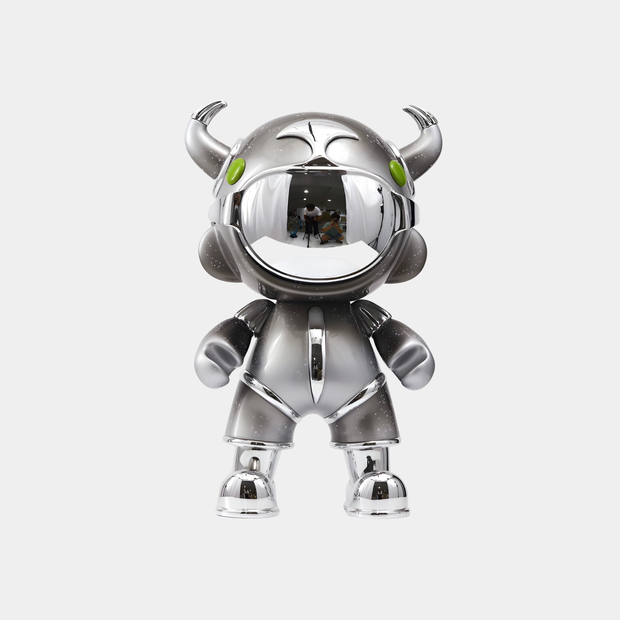 The Giant Sculptures Dark Chrome Suit Astro Devil Figure - 48cm stands upright on a white background, featuring a shiny silver finish, green eyes, two small horns, large round hands, and a reflective dark chrome suit for a bold look.
