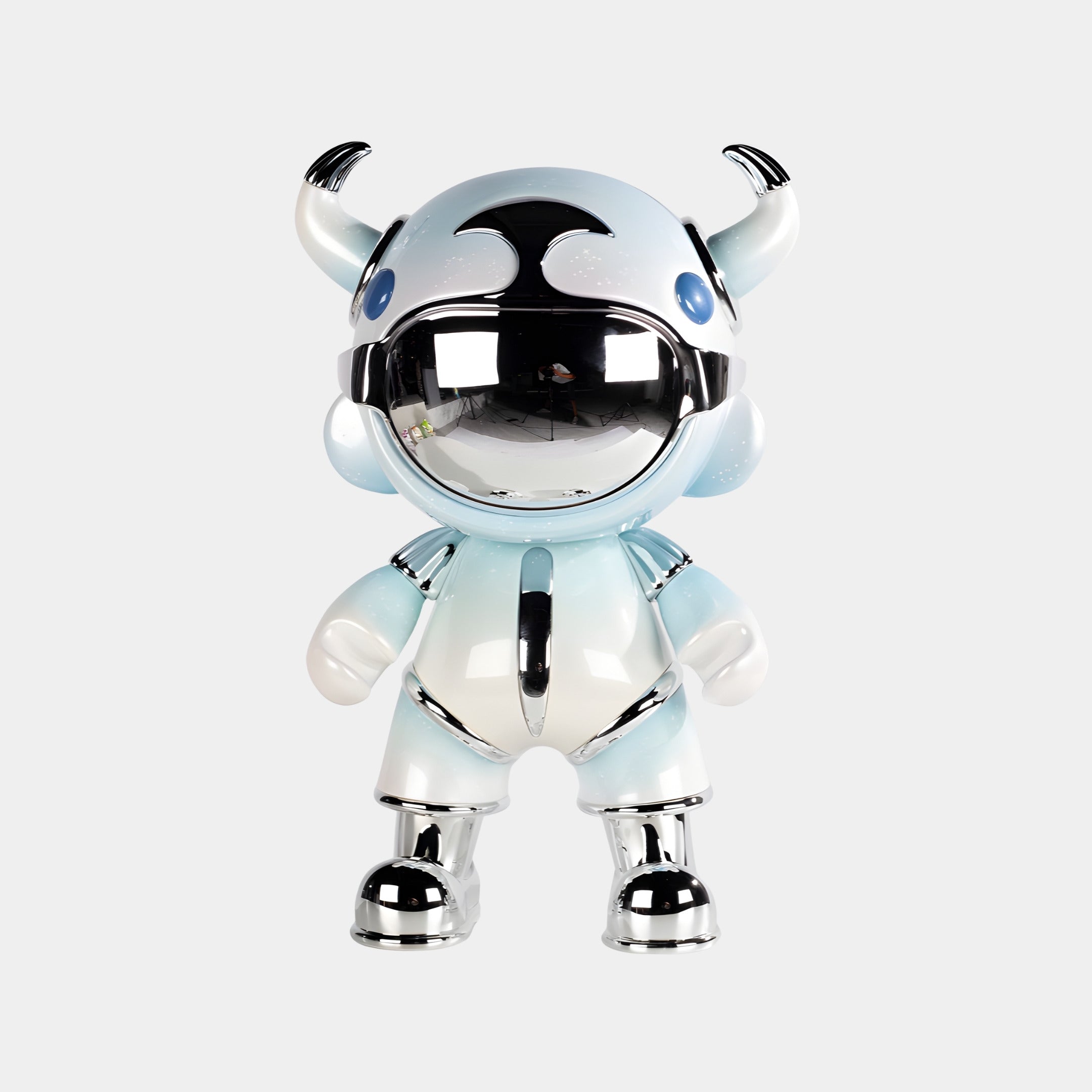 The Giant Sculptures Sky Blue Suit Astro Devil Sculpture (80cm) features a metallic, futuristic toy figure with a mirrored chrome visor and horned helmet, standing against a plain light background.