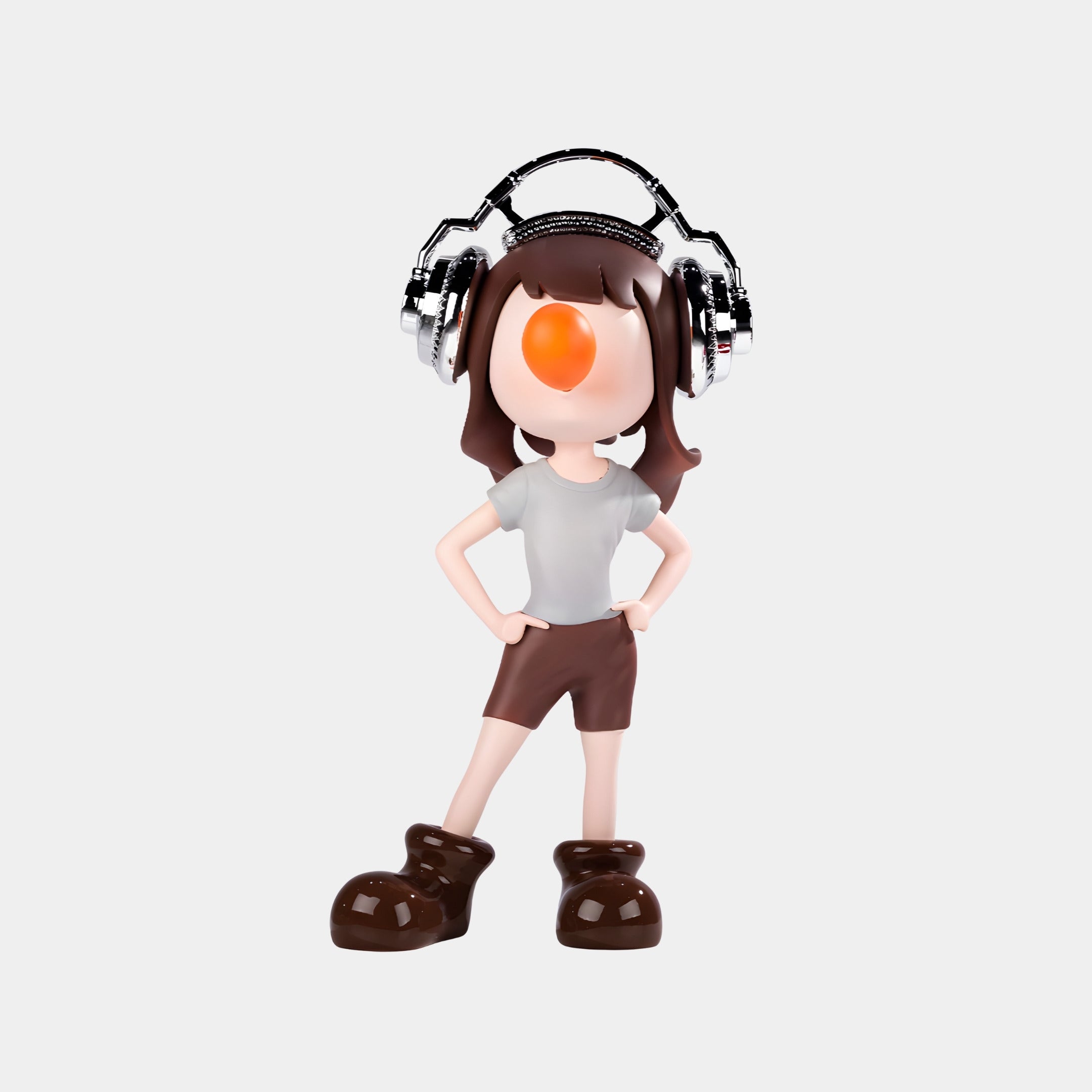 The Giant Sculptures Caramel Pop Vibella Chrome Headset Figure (60cm) features a playful cartoon character with an orange nose, white shirt, brown shorts, oversized brown shoes, and metallic headset standing on a plain white background.
