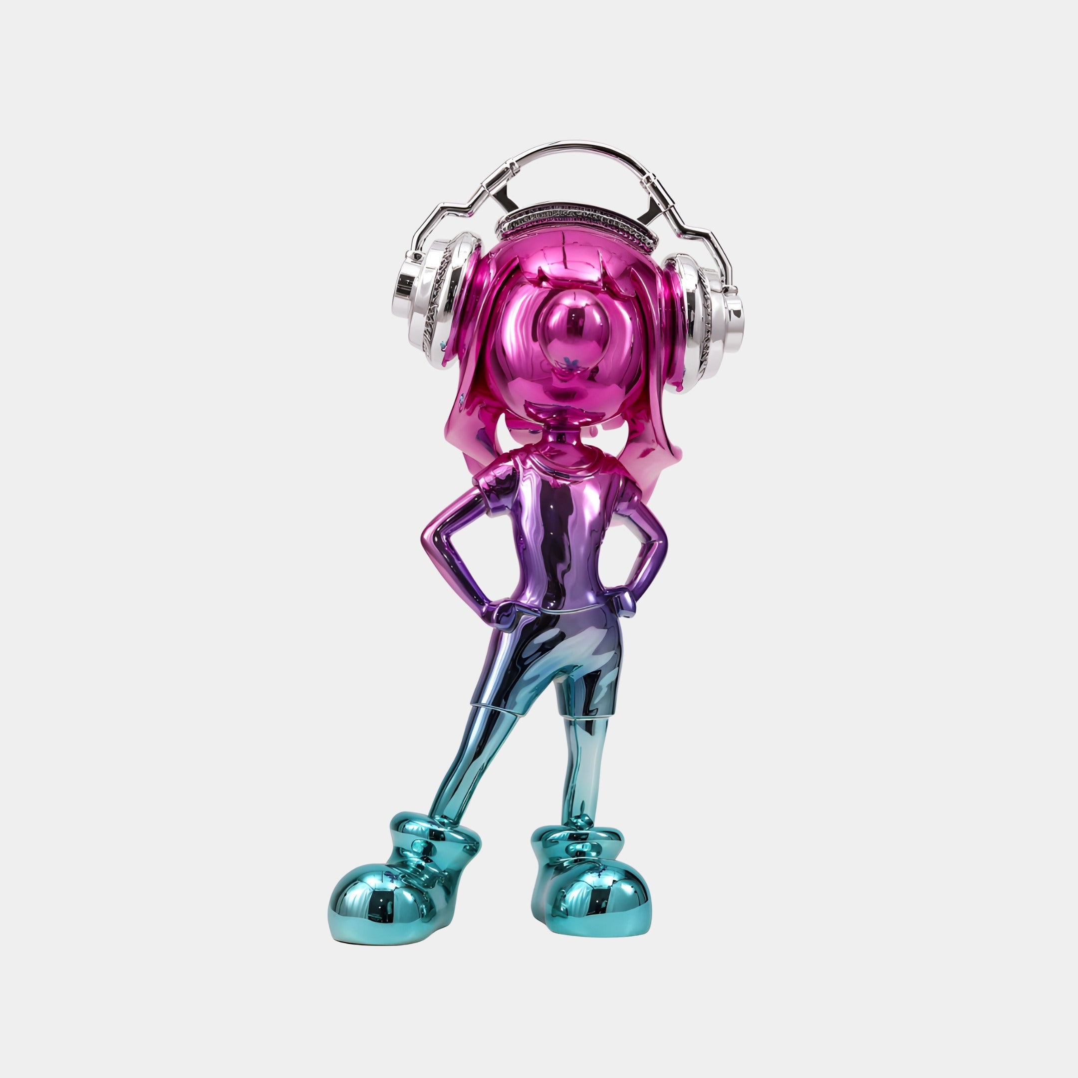 The Giant Sculptures Fuchsia Chrome Vibella Electroplated Figure (60cm) features a cartoon-like character with fuchsia chrome hair, silver headphones, blue shoes, and hands on hips, boldly standing against a plain white background.