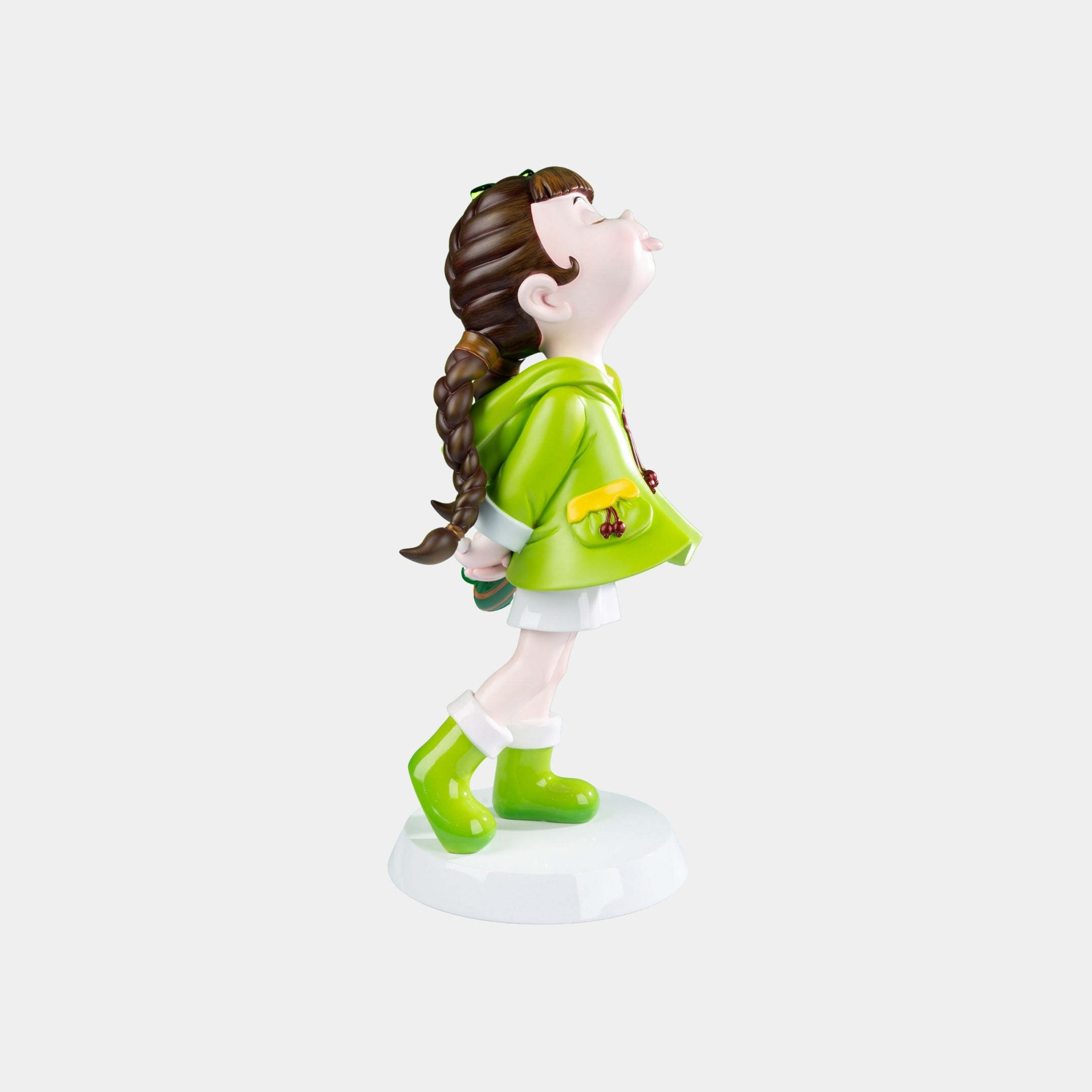 The Meadow Green Lulabelle Sculpture - 60cm by Giant Sculptures showcases a girl in a green hooded coat and boots on a white base, made from eco-friendly polyurethane.