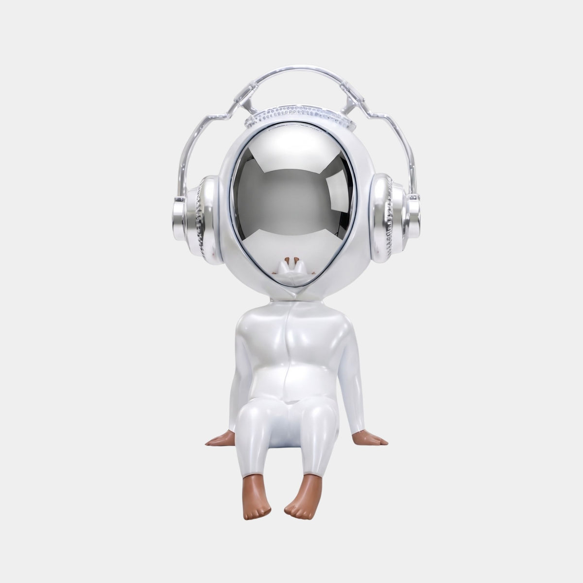 The Giant Sculptures Arctic White Alien Beats Figure (55cm) features a shiny, futuristic doll with a large reflective helmet and oversized headphones, seated with brown hands and feet visible against a plain white background.