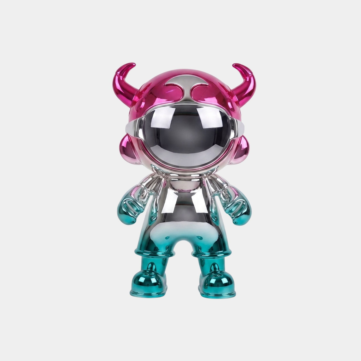 The Giant Sculptures Pink & Teal Electroplated Astro Devil Figure (35cm) features a chrome-like teal body, pink horned helmet, and teal gloves and boots—reflecting surroundings and ideal as a collectible art piece.