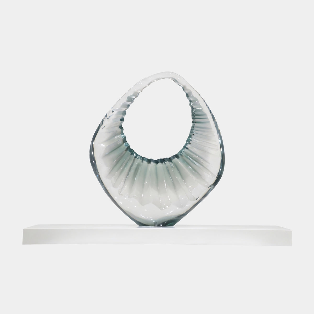Pale Green Fluted Open Ring Resin Sculpture (100cm) by Giant Sculptures, a fluted ring form shading from clear to grey-green, on a long marble base against a plain white background.