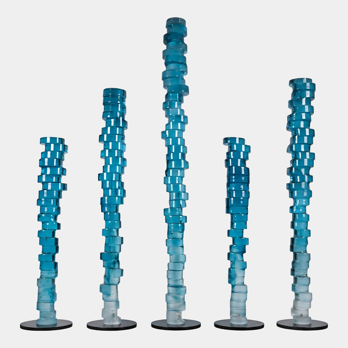 Five Blue to White Stacked Slab Resin Columns of varying heights on round bases, each with twisting square slabs fading from teal to white, on a plain white background.