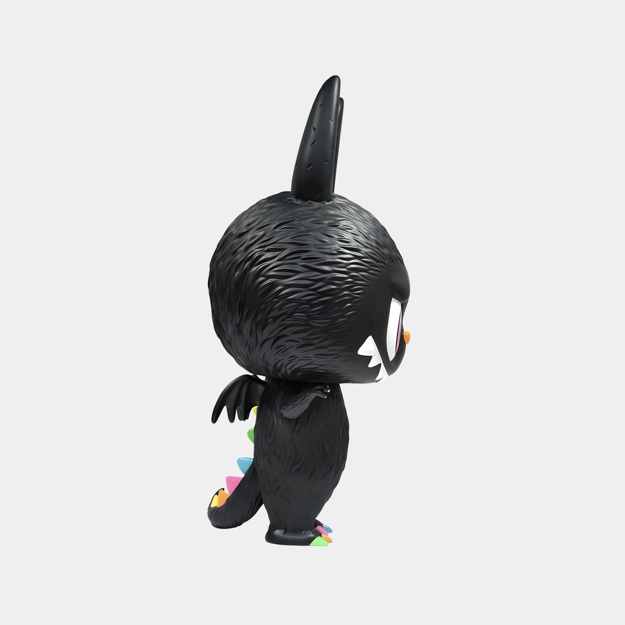 A side view of The Monster Zimomo Titan Labubu Sculpture by Giant Sculptures—70cm, black and furry with one large ear, white eyes, sharp teeth, and colorful spikes—makes a striking interior decor piece against a plain white background.