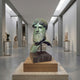 Classical Bearded Male Bust by Giant Sculptures in verdigris bronze on a dark marble plinth, displayed in a gallery with sculptures along the walls.