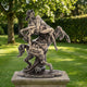 Classical Centaur and Nude Female Figure Bronze Sculpture by Giant Sculptures, 80cm, shown on a stone plinth in a sunlit garden with trees and hedges.