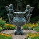 Classical Cherub and Urn Bronze Sculpture by Giant Sculptures, 120cm, with verdigris patina and two winged cherubs on the rim, set on a garden path beside marigolds.
