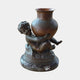 Classical Cherub Child and Urn Bronze Sculpture by Giant Sculptures, showing the dark patina cherub crouched on a rocky base lifting a reddish-brown urn.